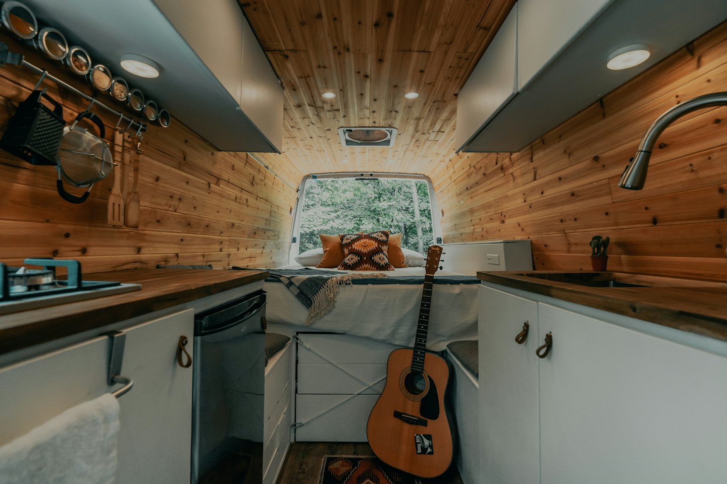 Interior acogedor de una furgoneta camper con paredes de madera y una cama.